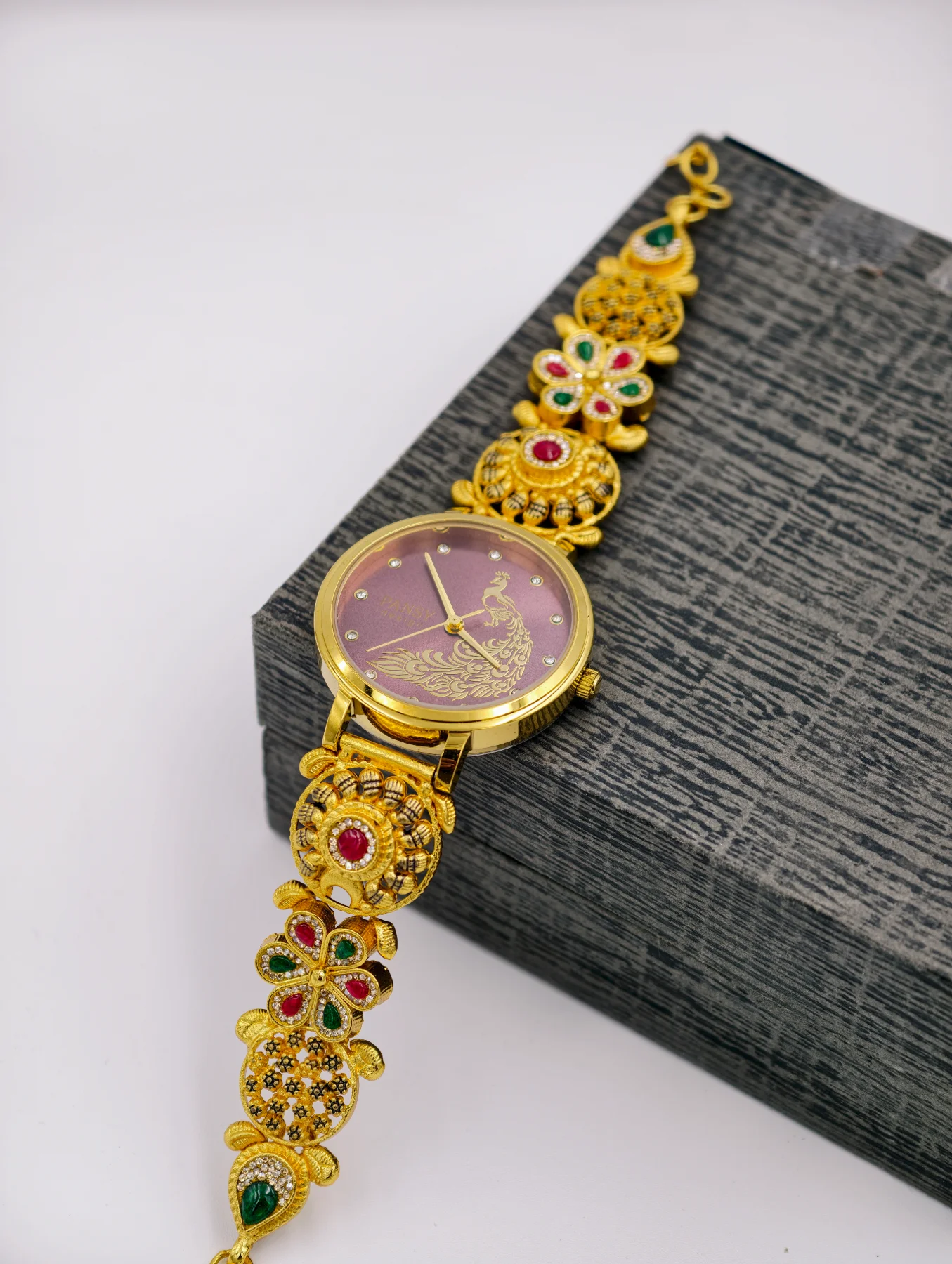 Gold polish silver watch featuring a purple dial with a peacock motif and intricately patterned floral links studded with stones.