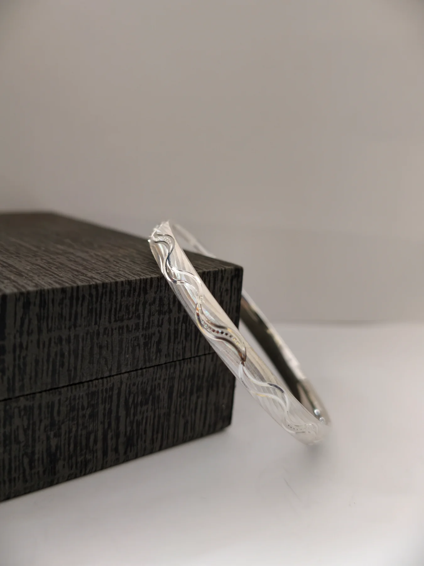 A glossy silver half round kada featuring a delicate CNC wave pattern and sparkling textured finish.