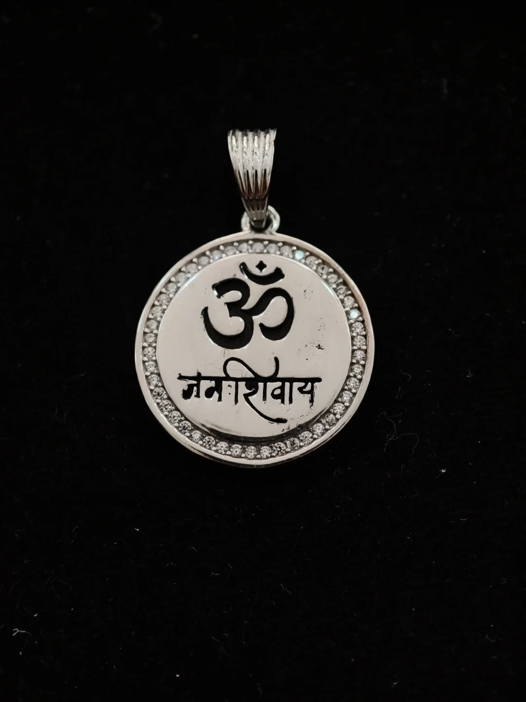 Round silver locket featuring Om and Namah Shivaya in black with a sparkling stone border.