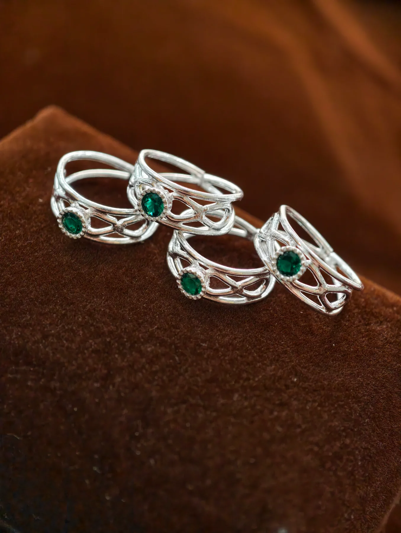 Silver bichiya featuring a delicate openwork pattern accented with a bright green stone.