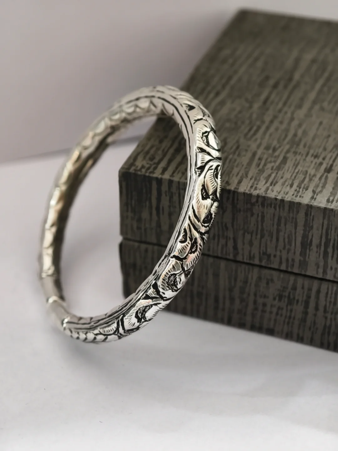 An oxidised silver kada with intricate floral carvings and traditional Rajasthani design.