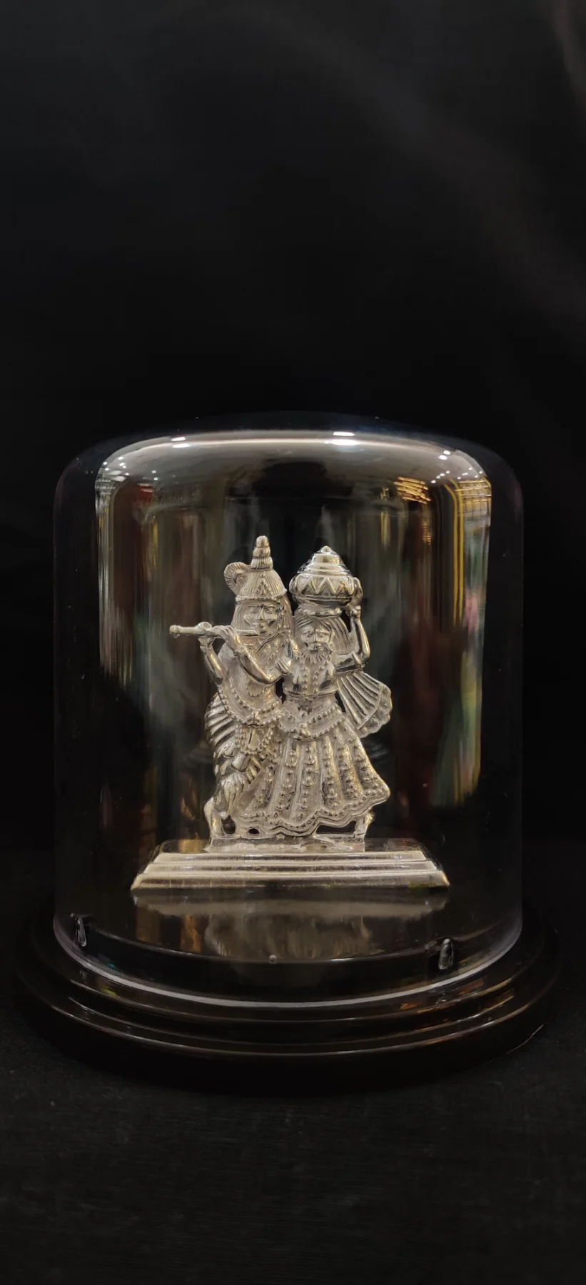 Detailed silver idol depicting deities playing instruments and carrying pots.