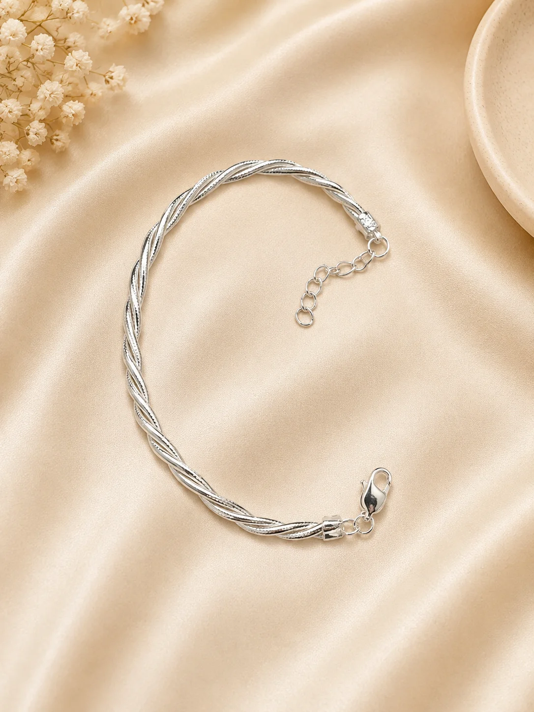 A glossy silver bracelet featuring a twisted wire pattern with an adjustable link chain and lobster clasp.