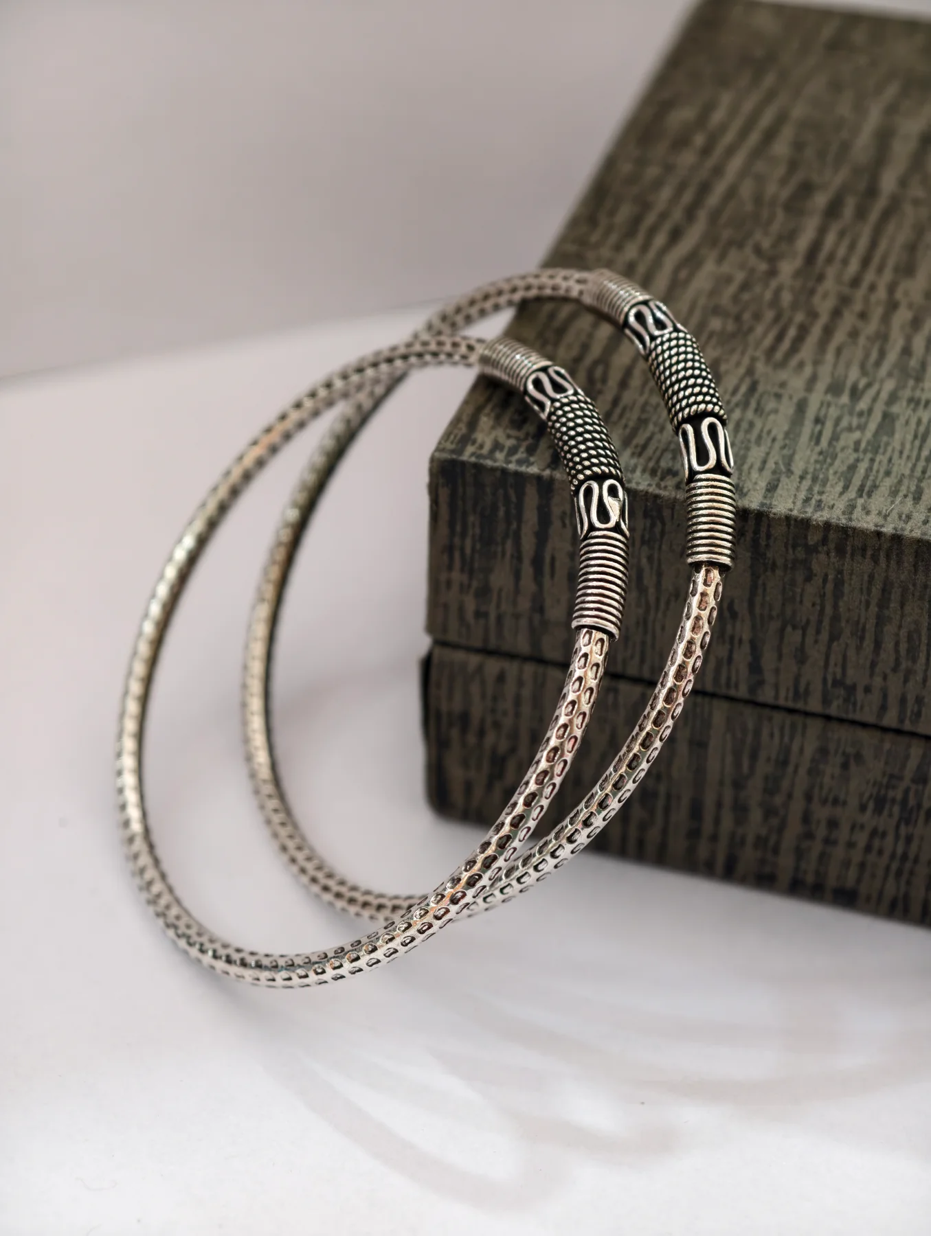 Pair of oxidised silver bangles with textured patterns and designer patterned sections.