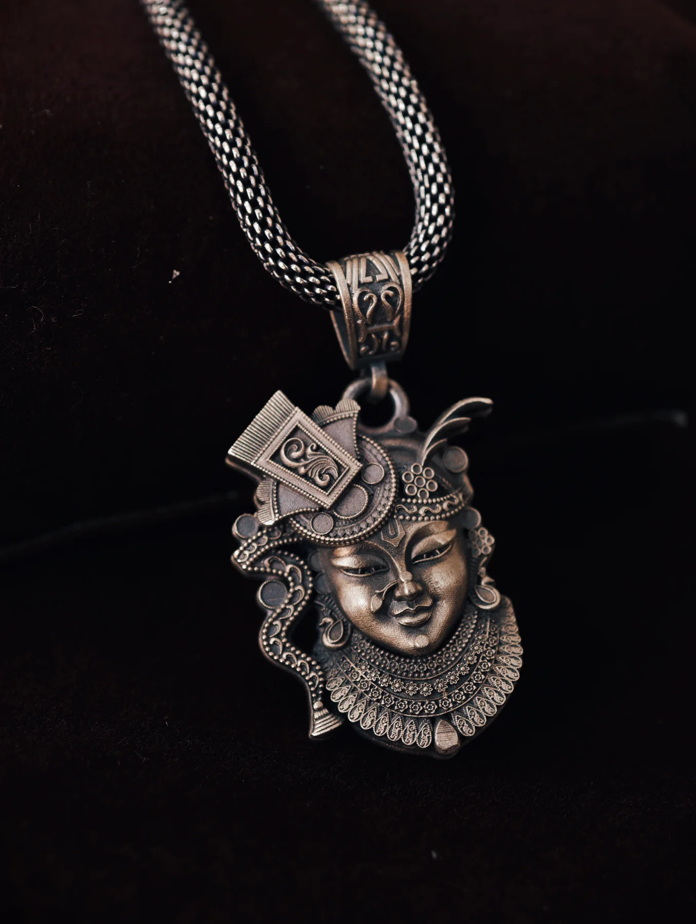 Oxidised silver locket featuring detailed deity motif with traditional ornaments and matching woven chain.
