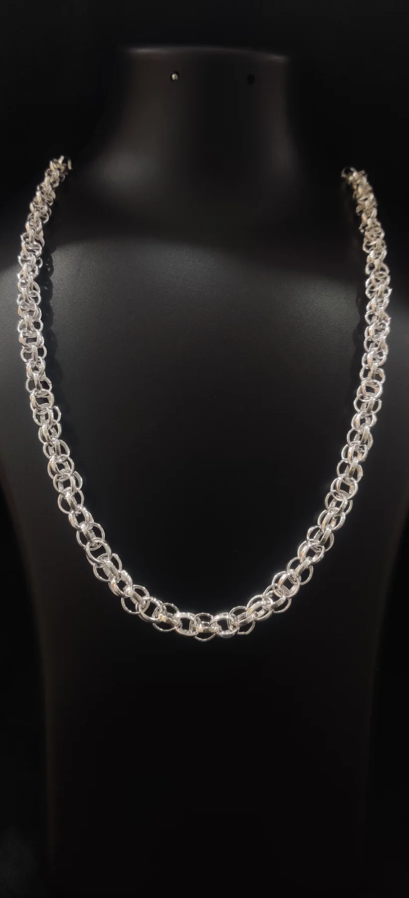 This shiny silver chain features an intricate interlocking round ring pattern with a polished finish.