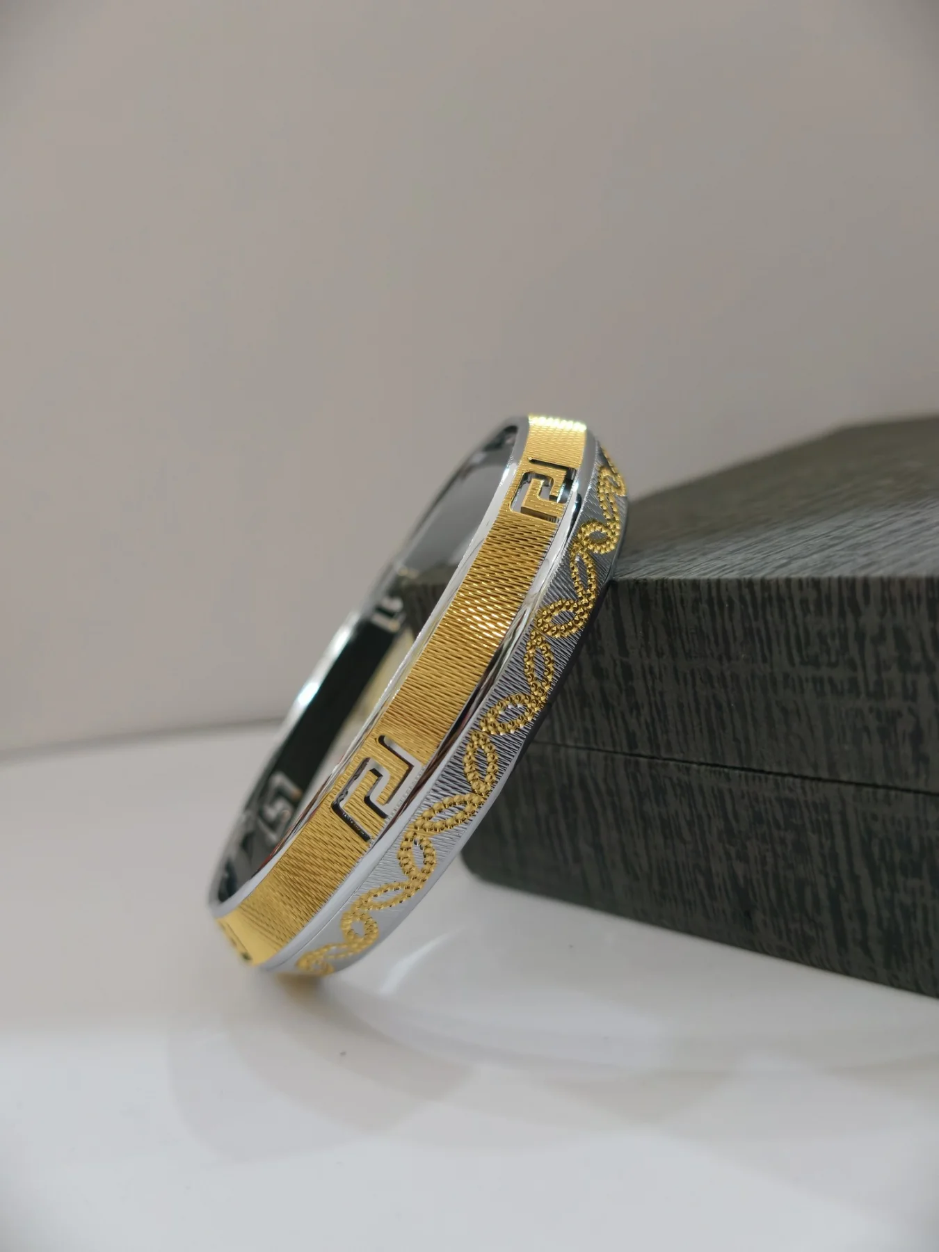 A broad silver kada featuring CNC textured patterns and gold polish finish.
