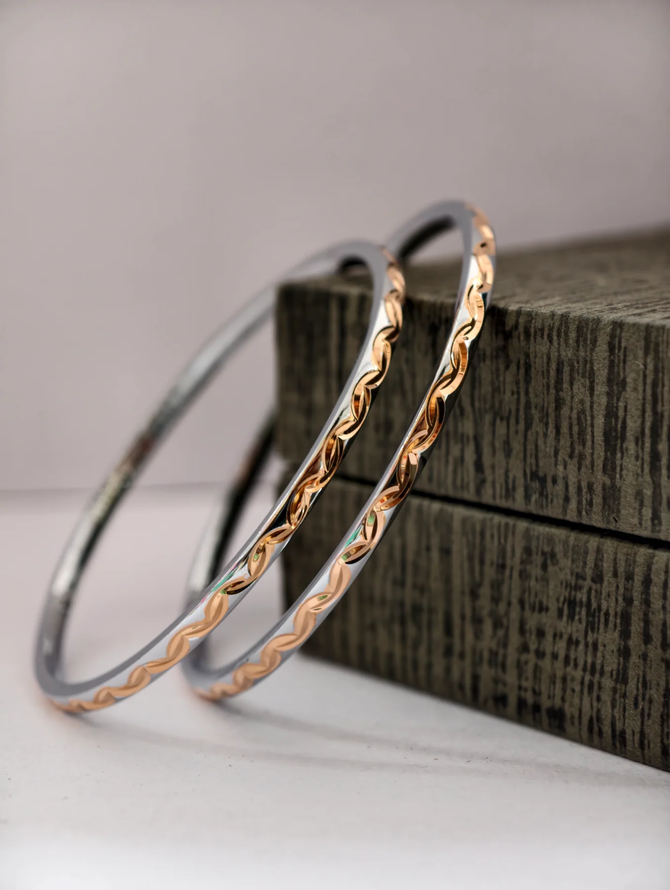 These simple silver bangles feature a shiny finish with a delicate engraved pattern along the outer edge.