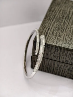 Silver snake bracelet featuring white stone paved patterns and mother of pearl segments.