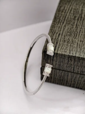 Silver bracelet with a glossy finish featuring white stones and shell design ends.