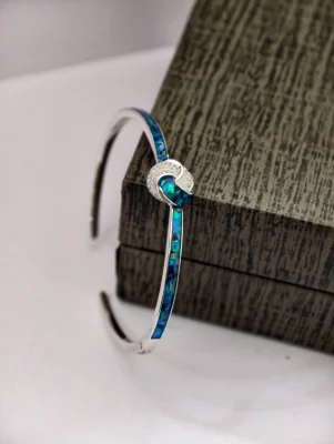 Silver snake bracelet featuring blue inlaid stones and a sparkling paved knot design in the centre.