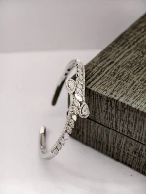 Silver snake bracelet featuring a curved pattern set with white stones and smooth mother of pearl motifs.