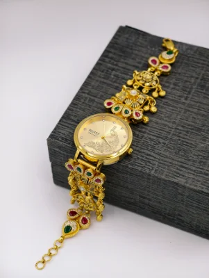 Gold polish silver watch bracelet featuring floral patterns, hanging beads, and red and green stones.
