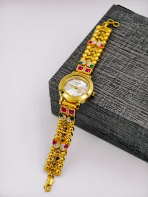 Gold polished silver watch featuring beaded straps, red square stones, green accents, and white stones.