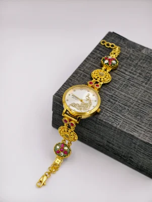 Gold polish silver watch with a peacock dial, floral pattern links, red and green stones, and clear crystals.
