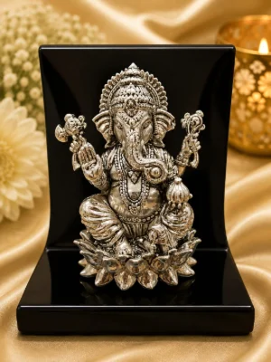Detailed silver idol of Lord Ganesha seated on a lotus flower with traditional ornaments and intricate carvings.