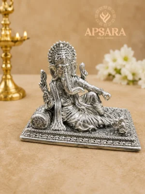 Oxidised silver Ganesha idol seated on a decorated rectangular base with intricate carving and a small mouse.