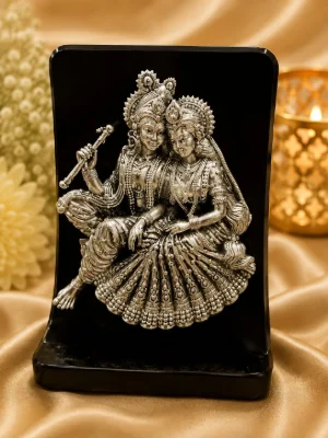 Detailed silver idol plaque showing Radha and Krishna with intricate carvings and ornate traditional attire.
