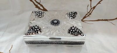 Square silver betel nut set featuring intricate engraved patterns, oxidised floral corners, and a central stone studded motif.