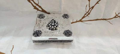 Square silver betel nut set with intricate floral motifs, four corner flower accents, and a central leaf design.