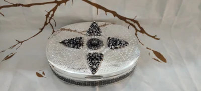 This oval silver betel nut set features intricate floral motifs and oxidized detailing across the surface.