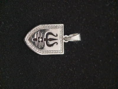 Shield shaped silver locket featuring an oxidised trishul and damru motif bordered with sparkling white stones.