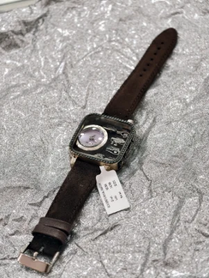 Silver luxury watch featuring a square dial with stone studded bezel and a brown leather strap.