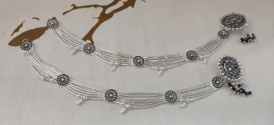 Oxidised silver payal featuring multi strand snake chains, floral spacers, hanging small bells, and large circular ends with ghunghroo hangings.