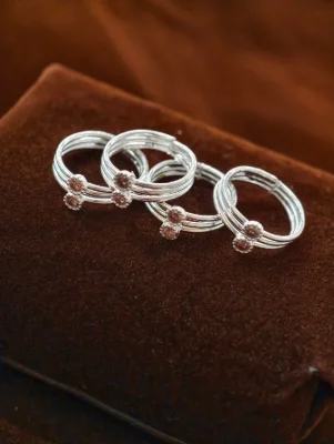 Set of four adjustable silver toe rings featuring a triple band design with two small round pink stones.