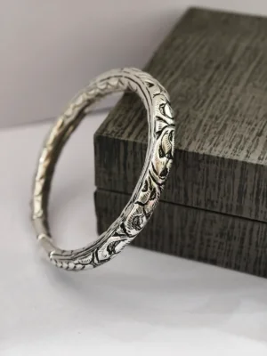 An oxidised silver kada with intricate floral carvings and traditional Rajasthani design.