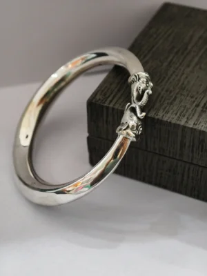 Polished silver kada featuring detailed elephant head motifs meeting at the center.
