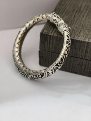 This round silver kada features intricate floral patterns with an oxidised finish and animal face ends.