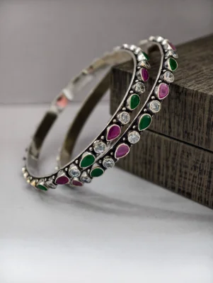 Oxidised silver bangles feature alternating round white stones and teardrop pink and green stones.