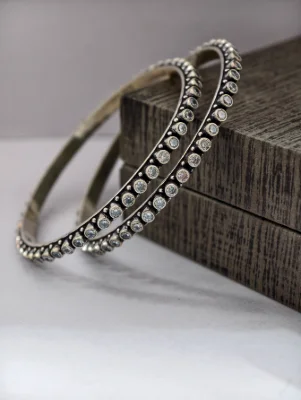 Oxidised silver bangles studded with sparkling white round stones in a neat row.