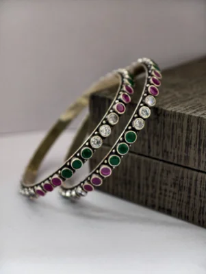 Oxidised silver bangles featuring alternating rows of round white, green, and pink stones.