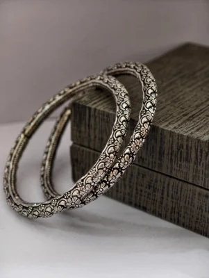 Pair of round silver bangles featuring detailed floral patterns with an oxidised finish.