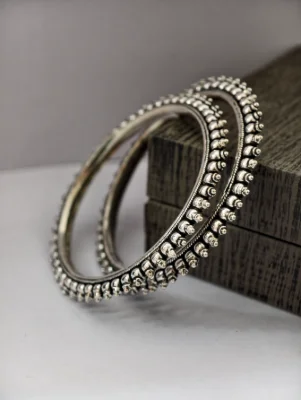 These round silver bangles feature an oxidised finish and a textured pattern with small raised bead details.