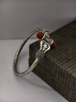 Oxidised silver kada featuring a trident motif, beaded texture, and brown rudraksha beads.