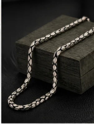 An oxidised silver chain featuring a patterned design with linked geometric shapes and a dark finish.