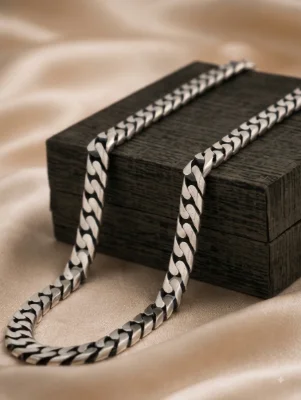 This is a thick flat oxidised silver chain featuring a classic interlinked pattern with a dark vintage finish.