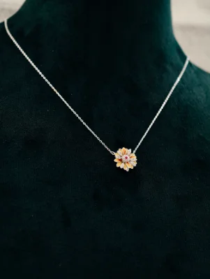 Silver chain with a flower pendant featuring white stones, red center, and yellow enamel petals.