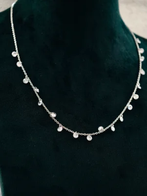 Delicate silver chain featuring dangling round stone drops with a shiny finish.