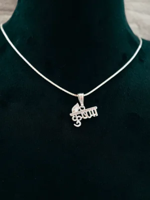 Silver chain featuring a Krishna Hindi script pendant with a flute and peacock feather studded with small white stones.