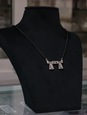 Elegant silver mangalsutra featuring a stone-studded geometric pendant attached to a black beaded chain.