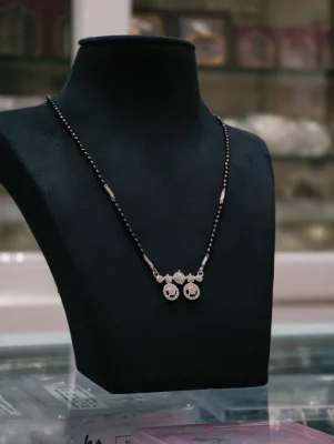Elegant silver mangalsutra featuring a black beaded chain with white stone studded locket pendants.