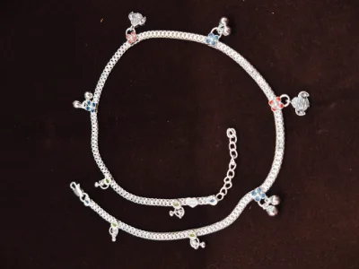 A delicate silver children payal featuring small colourful flower charms and tiny hanging bells.