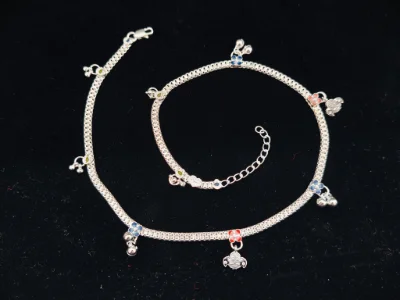 This silver children payal features a chain with colourful floral charms and tiny hanging bells.
