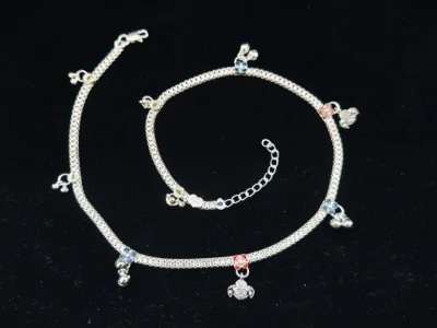 Silver children kardhan featuring linked chain, colorful enamel flower motifs, small hanging bells, and black evil eye beads.