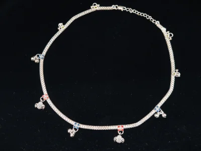 This silver children payal features a chain with colourful floral charms and small hanging silver bells.