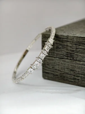 A silver stone kada bracelet featuring alternate square and marquise white stones set in a curved design.